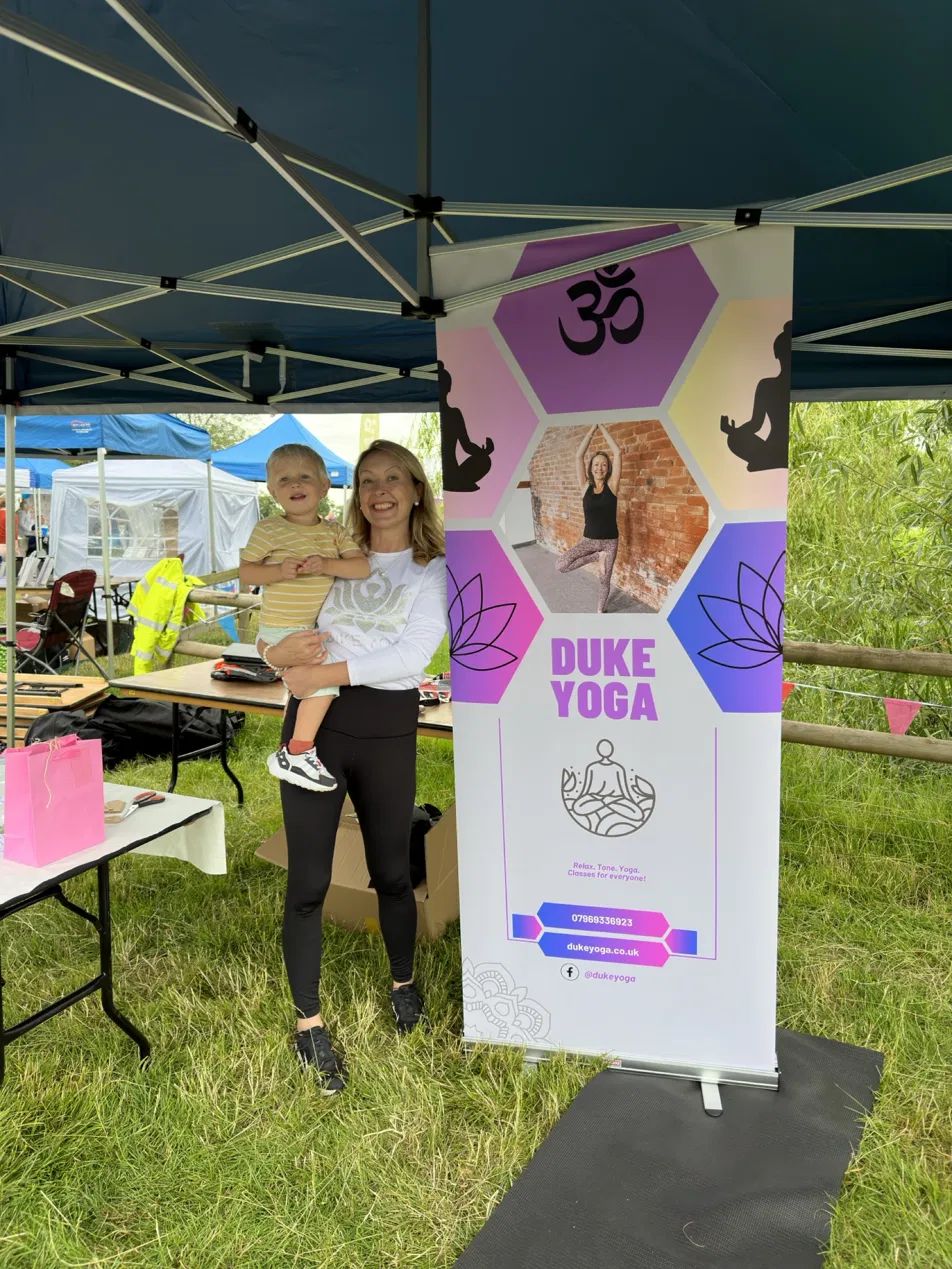 Fiona beside the Duke Yoga banner at a community event